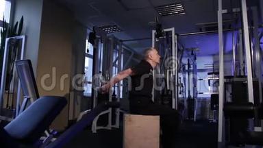 一个同龄的人在健身房为背部做关节体操。 后面手臂伸直.. 复制空间。